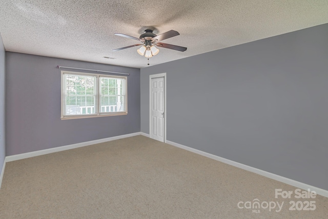 carpeted spare room with a textured ceiling, visible vents, a ceiling fan, and baseboards