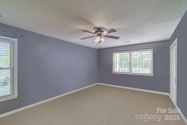 carpeted empty room featuring a ceiling fan, visible vents, a textured ceiling, and baseboards