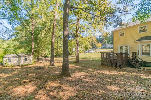 view of yard featuring fence, a storage unit, an outdoor structure, and a wooden deck