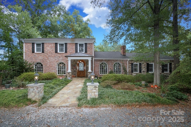 view of front of house featuring brick siding and a chimney