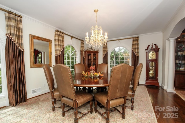 dining room featuring ornamental molding, wood finished floors, decorative columns, and a chandelier