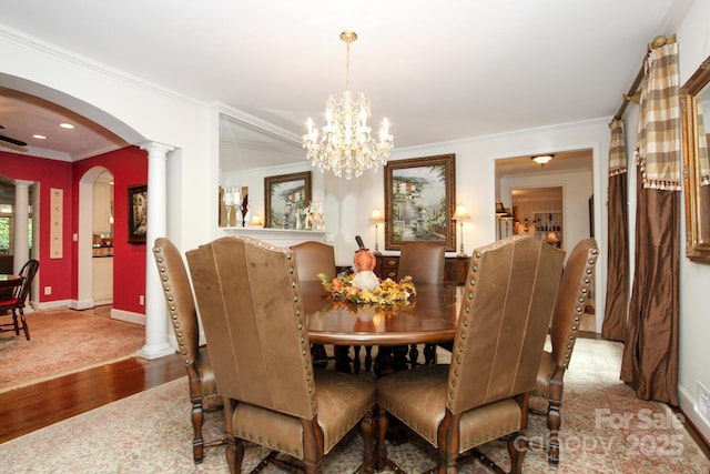 dining area with a notable chandelier, ornamental molding, wood finished floors, arched walkways, and baseboards