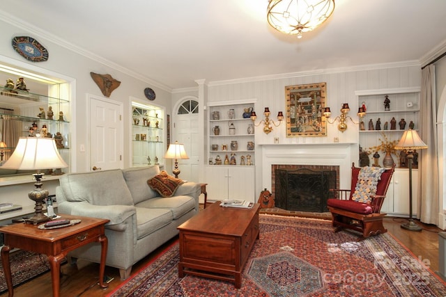 living room with built in features, wood finished floors, a fireplace, and ornamental molding