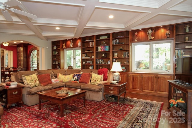 living room featuring wood finished floors, coffered ceiling, ornate columns, arched walkways, and ceiling fan