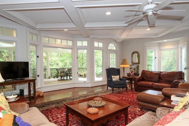 living area featuring wood finished floors, a healthy amount of sunlight, and coffered ceiling