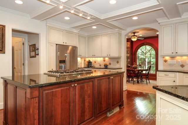 kitchen featuring stainless steel appliances, arched walkways, coffered ceiling, and a ceiling fan