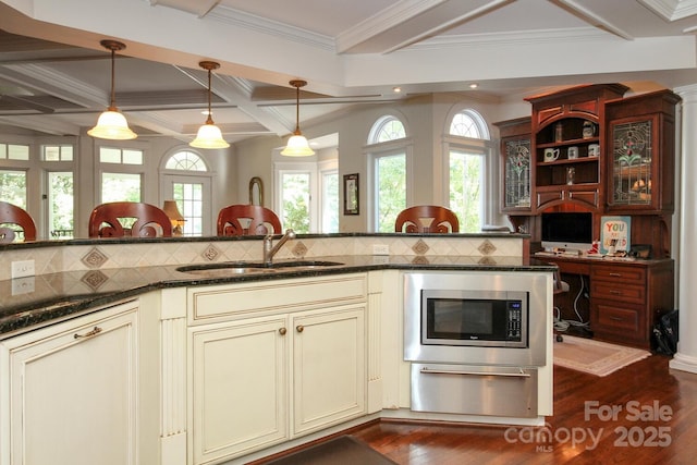 kitchen featuring dark wood-type flooring, a sink, stainless steel microwave, cream cabinets, and coffered ceiling