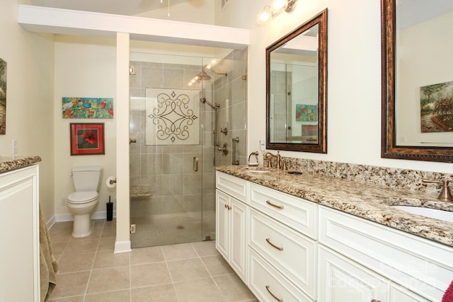 bathroom featuring toilet, double vanity, a stall shower, tile patterned floors, and a sink