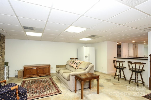 living room featuring a drop ceiling, baseboards, and visible vents