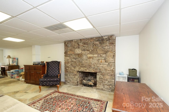 living room with a stone fireplace and a paneled ceiling