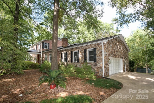 view of front of property with stone siding, driveway, a chimney, and a garage