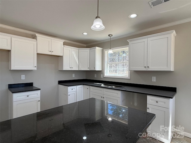 kitchen with a sink, white cabinets, dark stone counters, decorative light fixtures, and crown molding