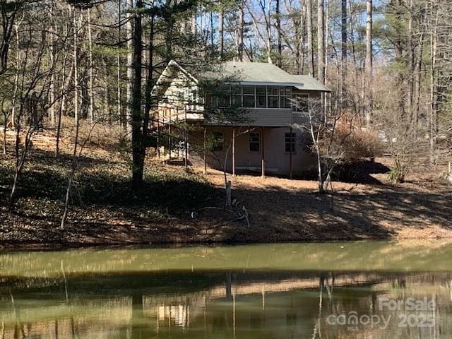 exterior space featuring a water view, a sunroom, and stairway