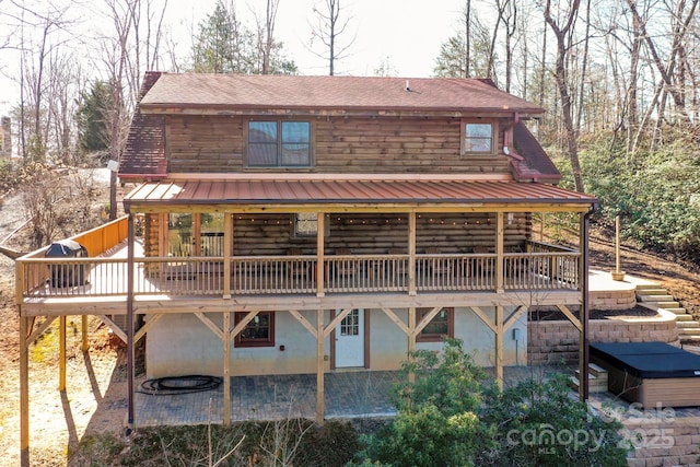 rear view of house with log exterior, a patio area, a wooden deck, and stucco siding