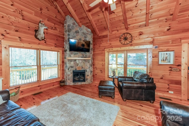 living area with wood walls, a fireplace, wood finished floors, wood ceiling, and beam ceiling