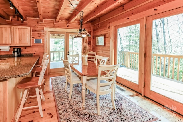 dining room featuring wooden ceiling, light wood-style flooring, wooden walls, french doors, and beamed ceiling