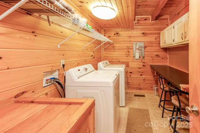 laundry area featuring wooden ceiling, cabinet space, wood walls, and washing machine and clothes dryer