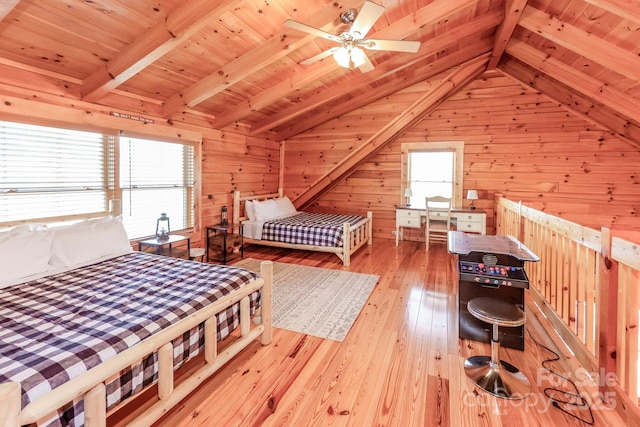 bedroom with vaulted ceiling with beams, wooden walls, multiple windows, and hardwood / wood-style floors