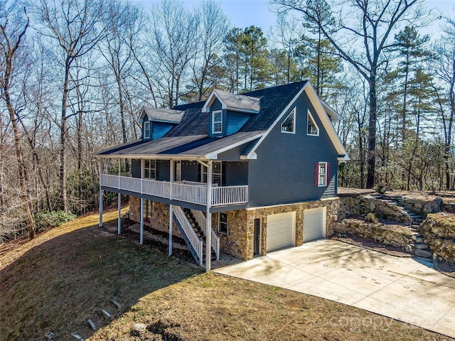 view of home's exterior featuring concrete driveway, stone siding, stairway, an attached garage, and a porch