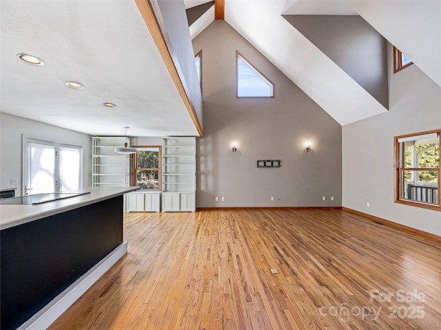 unfurnished living room featuring light wood-style floors, plenty of natural light, and baseboards