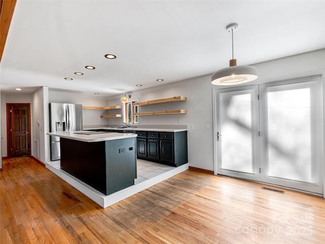 kitchen featuring visible vents, light countertops, light wood-type flooring, stainless steel fridge with ice dispenser, and open shelves