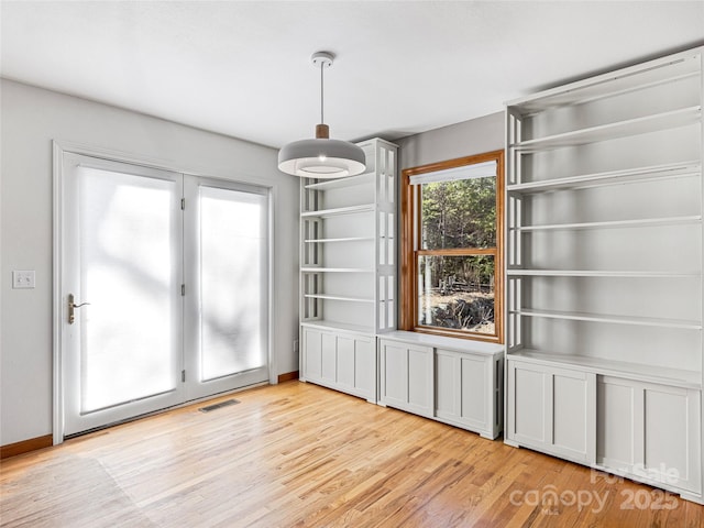 unfurnished dining area featuring light wood finished floors, visible vents, and baseboards