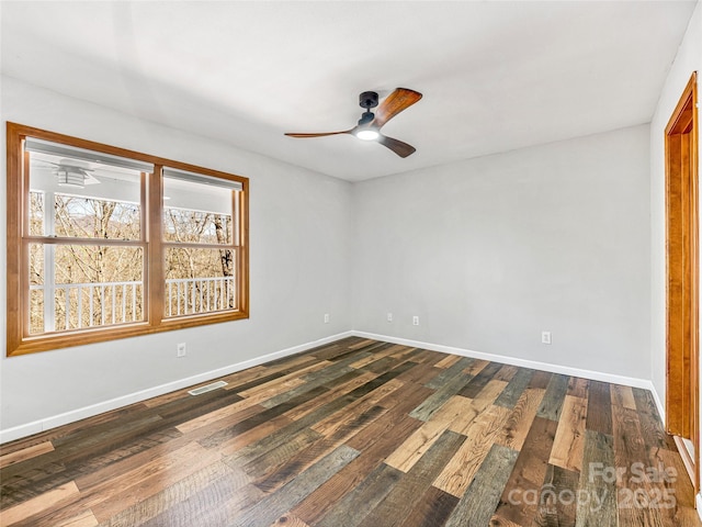 spare room with ceiling fan, dark wood-style flooring, and baseboards