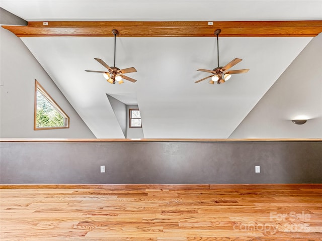 empty room with ceiling fan, vaulted ceiling, and wood finished floors