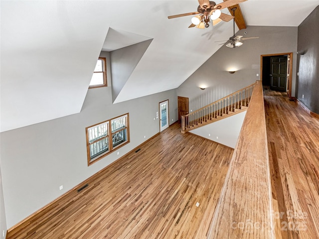 unfurnished living room with visible vents, stairway, wood finished floors, and beam ceiling