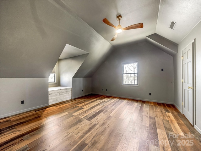 bonus room featuring lofted ceiling, wood finished floors, visible vents, and a healthy amount of sunlight