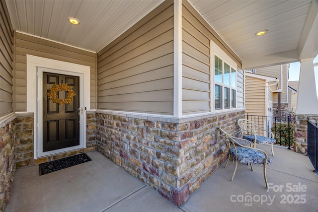 property entrance with stone siding and a porch