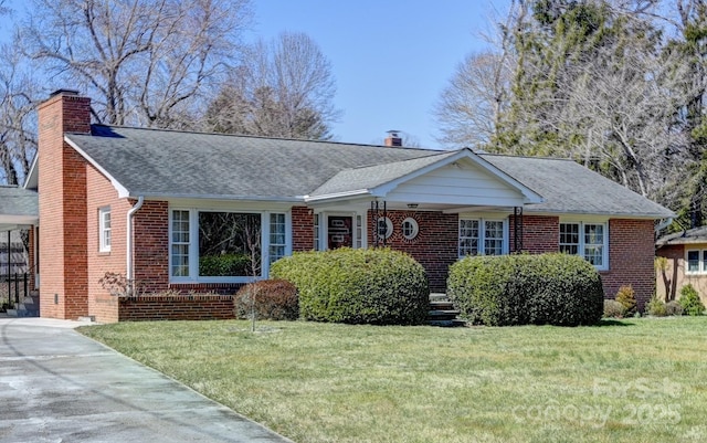 ranch-style home featuring brick siding, roof with shingles, a chimney, and a front yard