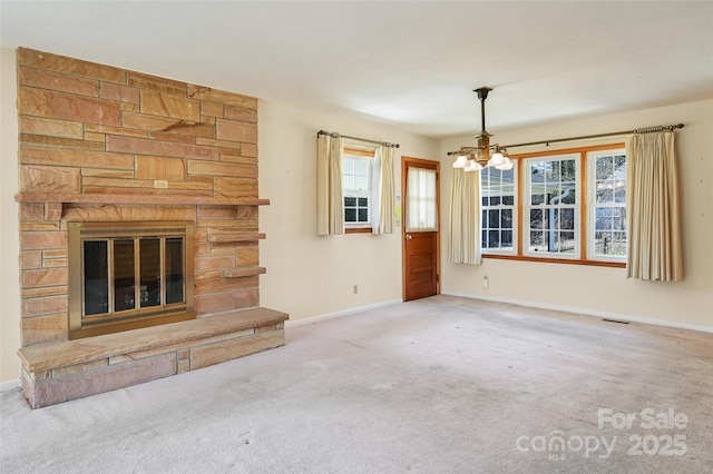 unfurnished living room featuring a fireplace, visible vents, an inviting chandelier, carpet flooring, and baseboards