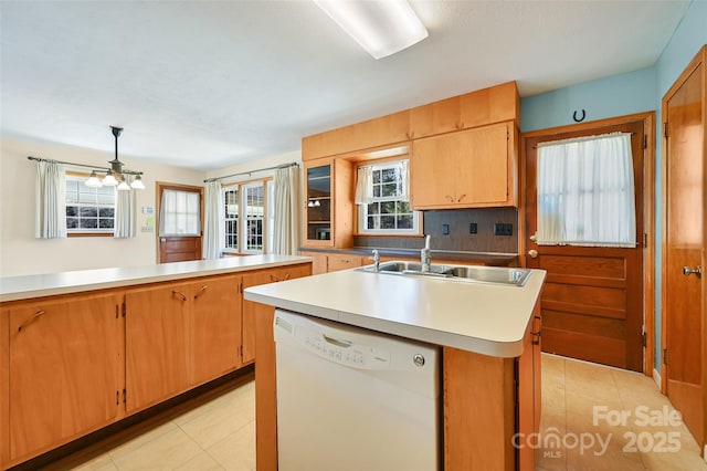 kitchen with a sink, light tile patterned floors, light countertops, and dishwasher