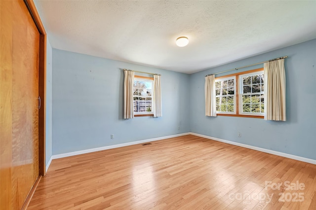 unfurnished room featuring a textured ceiling, baseboards, and wood finished floors