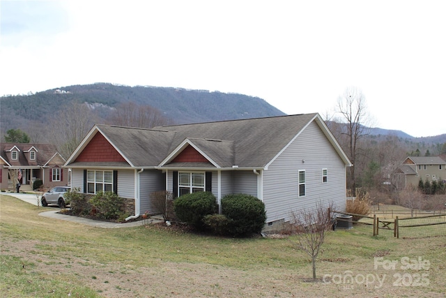 view of front of house with roof with shingles, crawl space, fence, a mountain view, and a front lawn