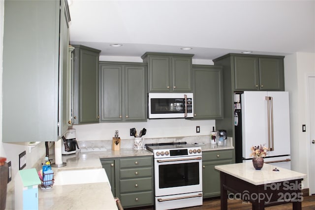 kitchen featuring green cabinets, white appliances, light stone countertops, and recessed lighting