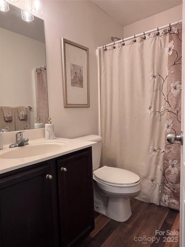 full bathroom with toilet, wood finished floors, and vanity