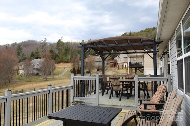 wooden terrace with outdoor dining area and a yard