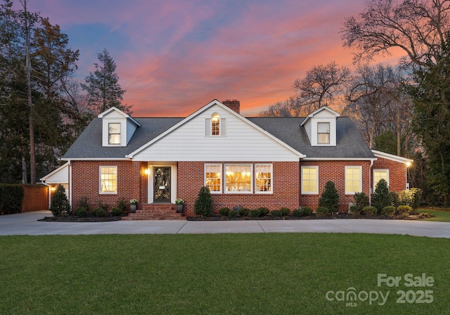 view of front of property featuring driveway, brick siding, and a front yard