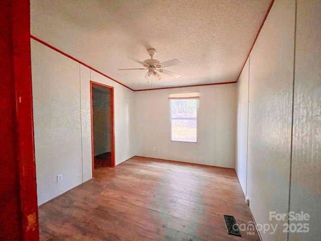 unfurnished bedroom with visible vents, crown molding, a textured ceiling, and wood finished floors