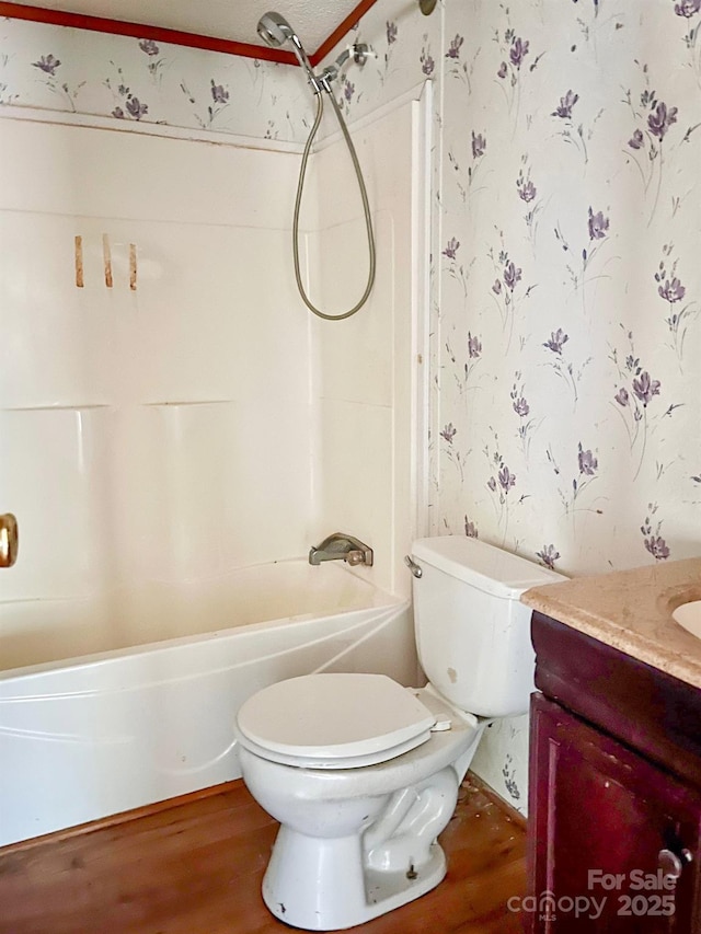 bathroom with toilet, wallpapered walls, wood finished floors, and vanity