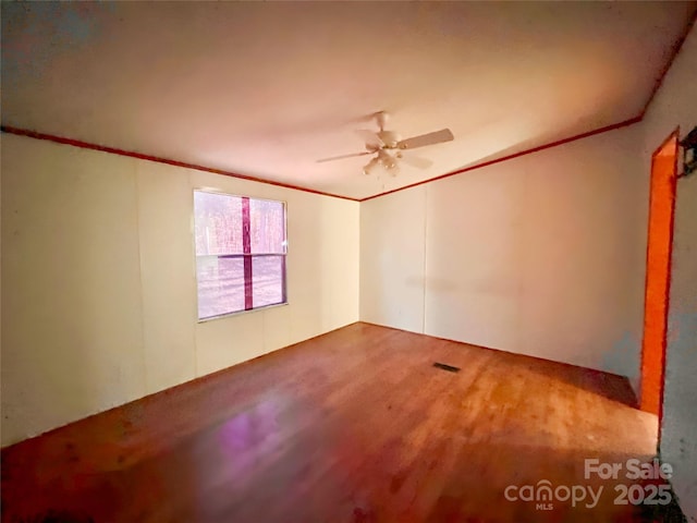 empty room featuring visible vents, a ceiling fan, crown molding, and wood finished floors