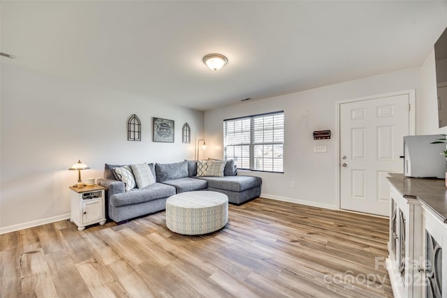 living room featuring light wood finished floors, visible vents, and baseboards