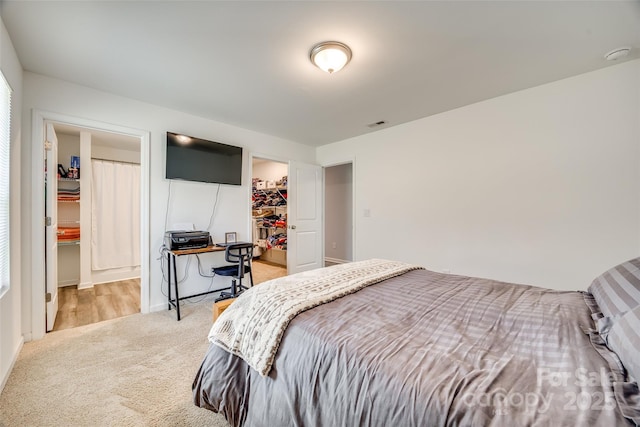 bedroom featuring a closet, light carpet, and a spacious closet