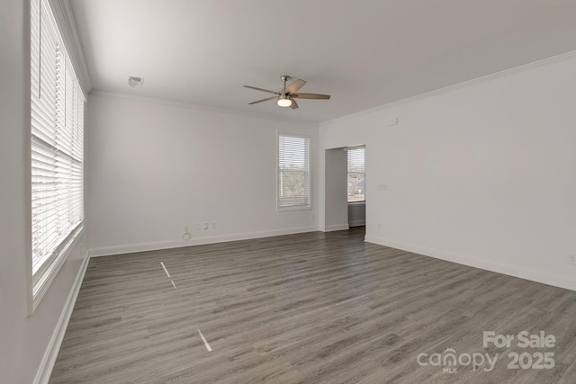 unfurnished room with ornamental molding, wood finished floors, a ceiling fan, and baseboards