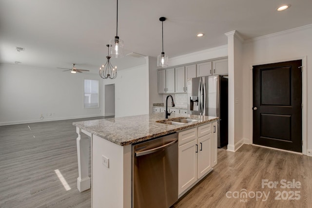 kitchen with stainless steel appliances, ornamental molding, light wood-type flooring, and a sink