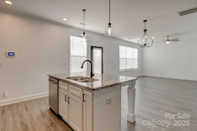 kitchen with light stone counters, light wood-style flooring, a sink, visible vents, and dishwasher