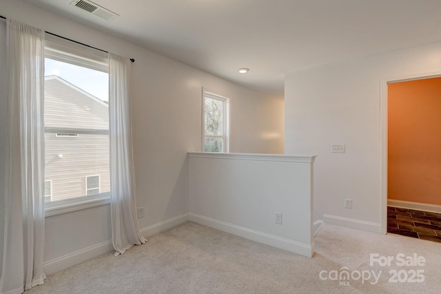 carpeted empty room featuring baseboards and visible vents