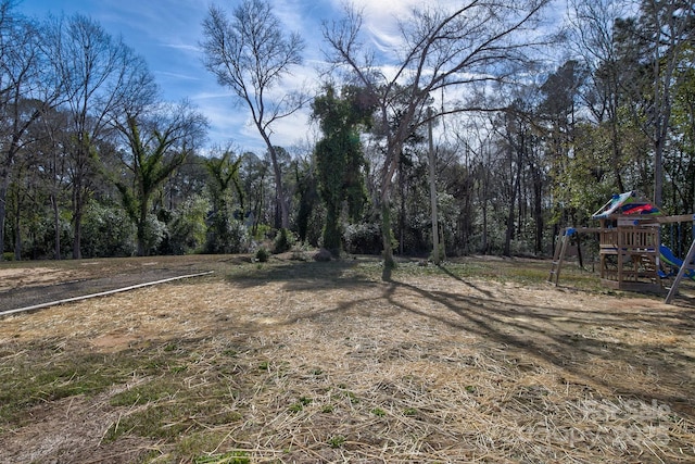 view of yard featuring a playground and a wooded view